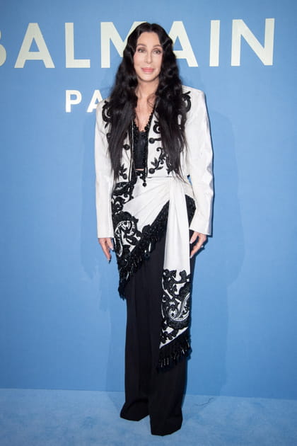 Cher en veste blanche nouée à la taille et pantalon noir