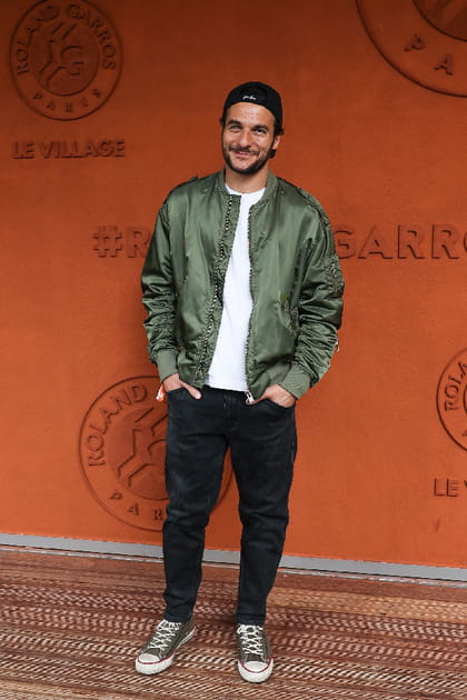 Amir en pantalon noir, polo blanc et bomber satin&eacute; vert