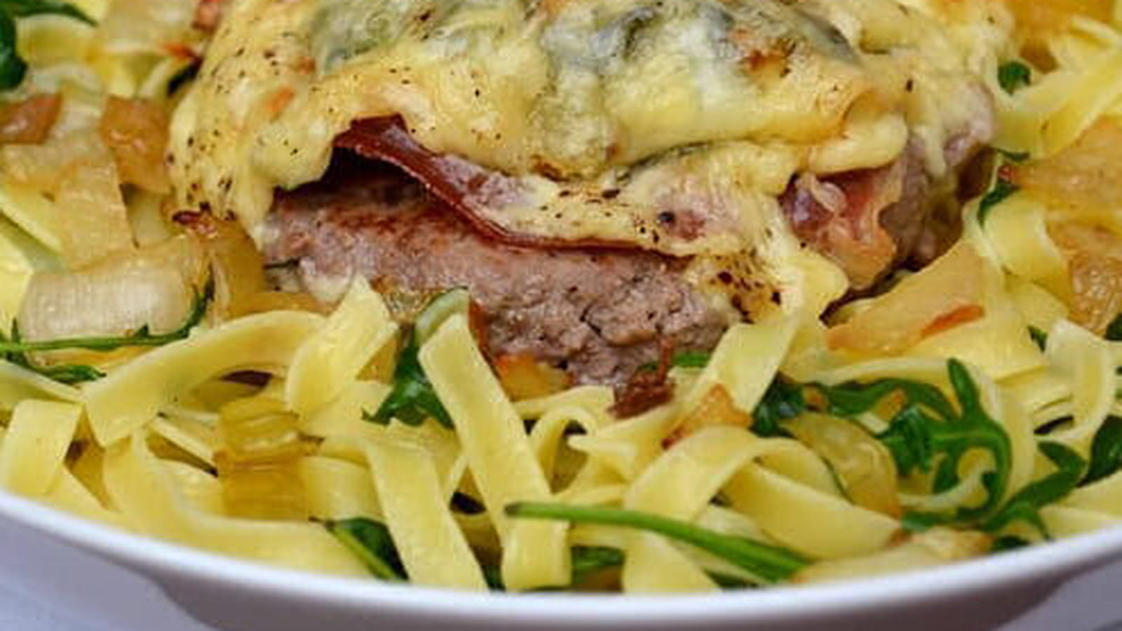 Steak haché gratiné aux oignons, jambon cru et fromage de Chimay, tagliatelle à la roquette