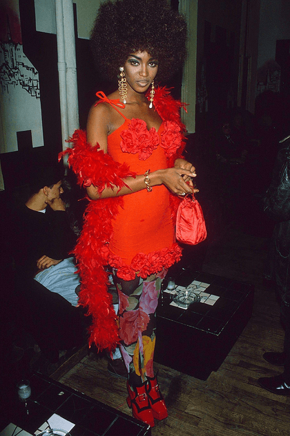 Naomi Campbell en robe courte rouge et collants fleuris