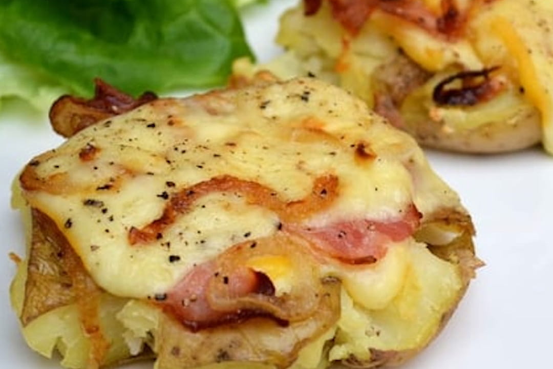 Pommes de terre au fromage à raclette, lard fumé et oignons grillés