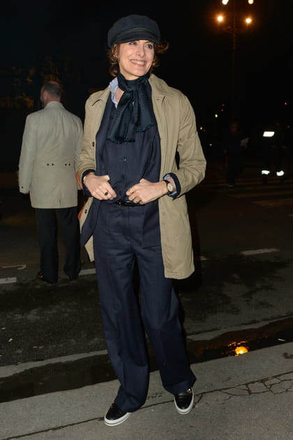 Inès de la Fressange en pantalon bleu marine, trench beige et casquette gavroche