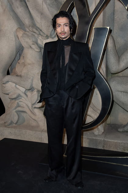 Daiki Tsuneta en ensemble de costume noir et chemisier transparent à col montant au défilé Saint Laurent