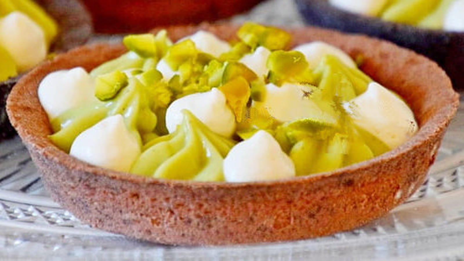 Tartelette garnie de crème pâtissière à la pistache sur un lit de caramel au beurre salé