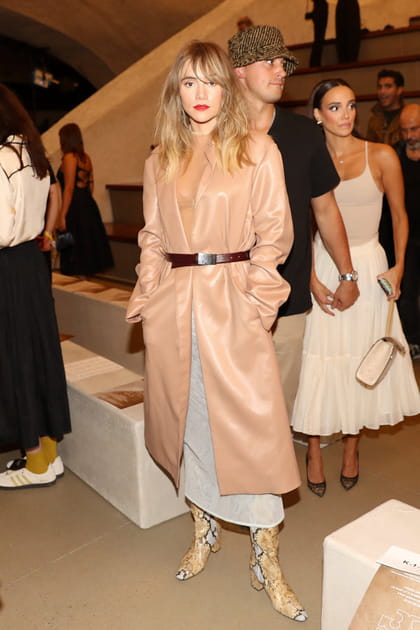 Suki Waterhouse en manteau en cuir rose poudr&eacute; et longue robe grise au d&eacute;fil&eacute; Tory Burch printemps-&eacute;t&eacute; 2024