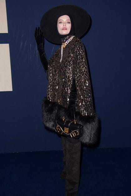 Camille Razat en manteau pailleté et fausse fourrure avec une capeline au défilé Balmain