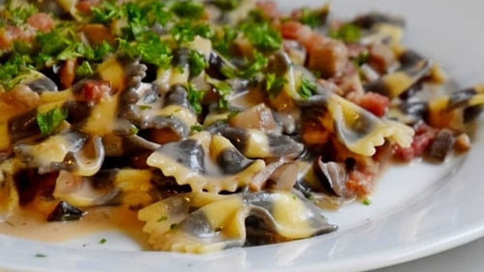 Pâtes papillon à l'encre de sèche aux champignons et lardons