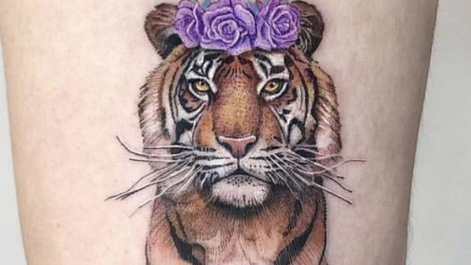Tigre et couronne de fleurs sur la cuisse