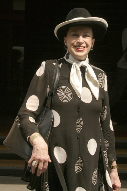 Geneviève de Fontenay en chapeau bicolore et chemise noire imprimée de cercles blancs