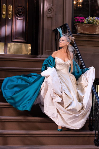 Carrie Bradshaw en robe de bal blanche, cape bleue et plume dans les cheveux