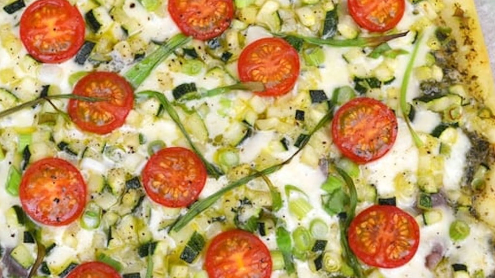 Pizza de courgette, jambon cru, tomates cerise, pesto et mozzarella