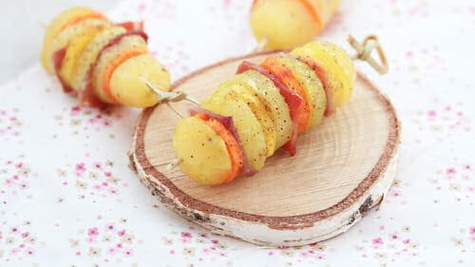 Brochettes de pommes de terre, carottes oranges et jaunes, jambon cru