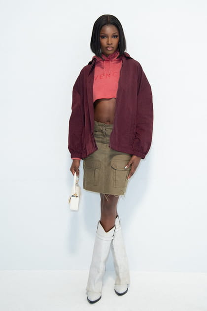 Leomie Anderson en pull court rose à écriture et jupe en jean kaki au défilé Givenchy