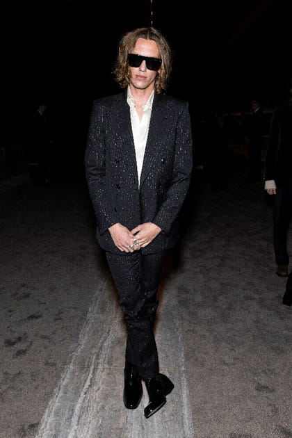 Jamie Campbell en costume noir &agrave; fines rayures blanches et lunettes de soleil rectangulaires