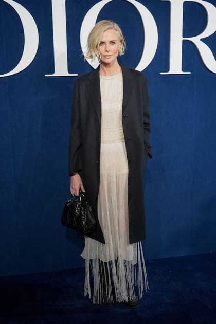 Charlize Theron en robe beige à franges et manteau noir Dior