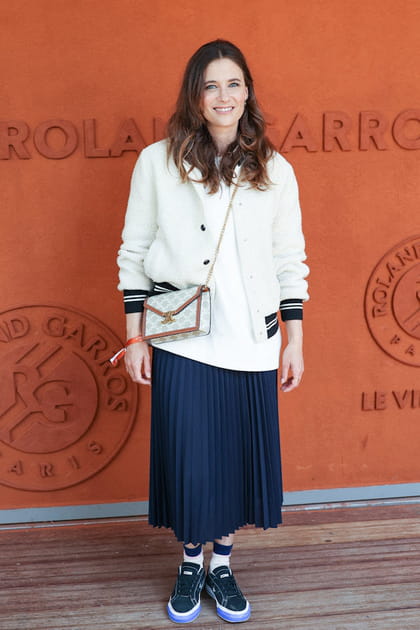 M&eacute;lanie Bernier en jupe pliss&eacute;e bleu marine et sac &agrave; main en bandouli&egrave;re