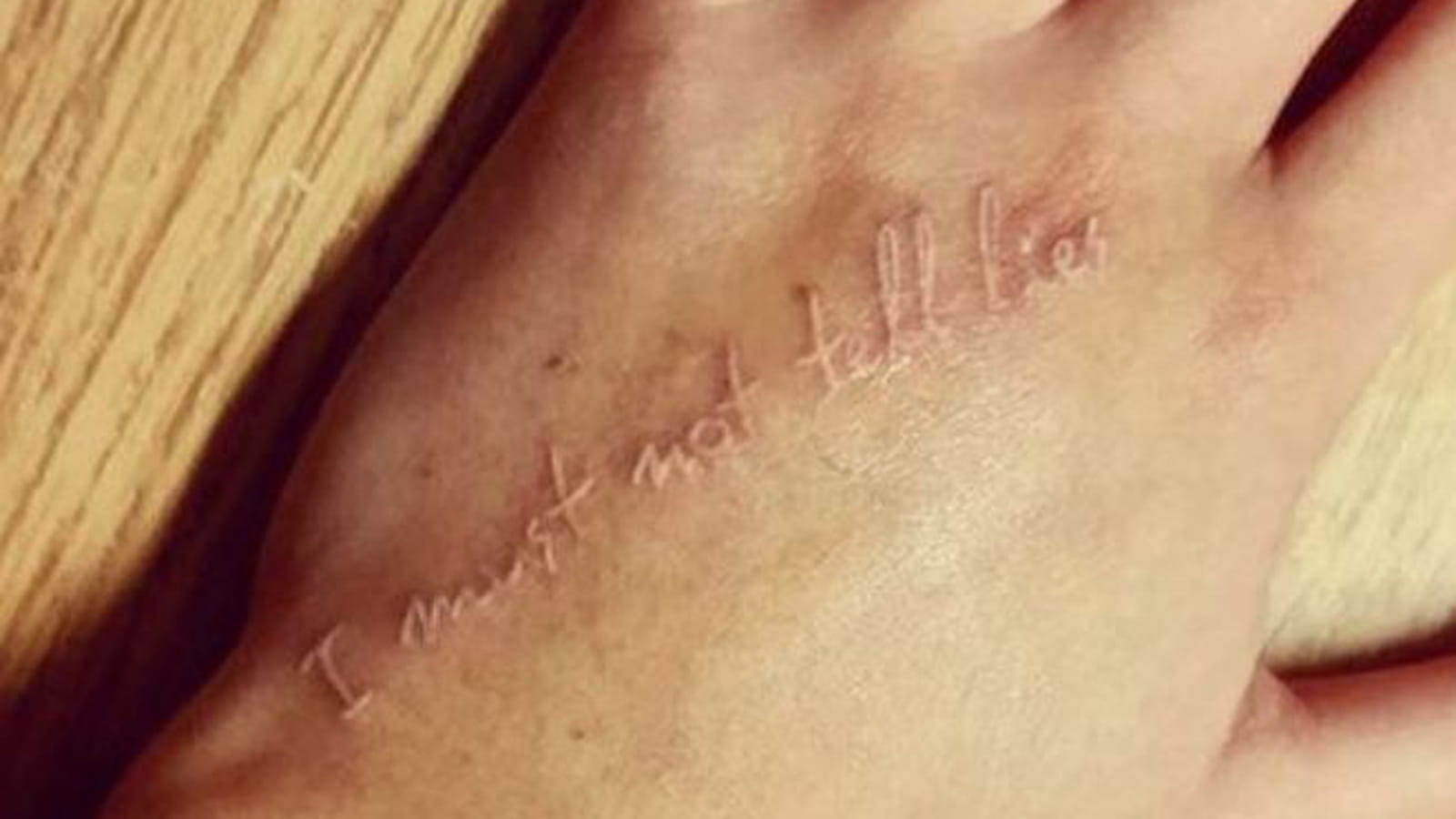 "I must not tell lies" à l'encre blanche sur la main