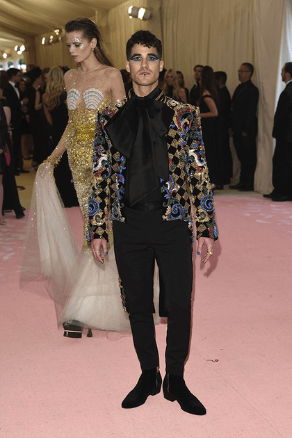 Darren Criss en chemise noire à col lavallière XXL et veste à paillettes