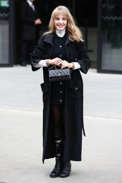 Arielle Dombasle en robe pull bleu marine et manteau noir au défilé Chanel haute couture printemps-été 2024
