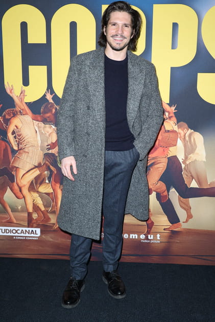 François Civil en pull noir et manteau long gris