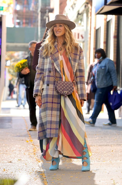 Carrie Bradshaw en manteau à carreaux, bottes bleues et robe à rayures