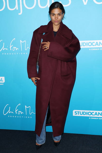 Tina Kunakey en manteau oversize bordeaux et escarpins satinés noirs