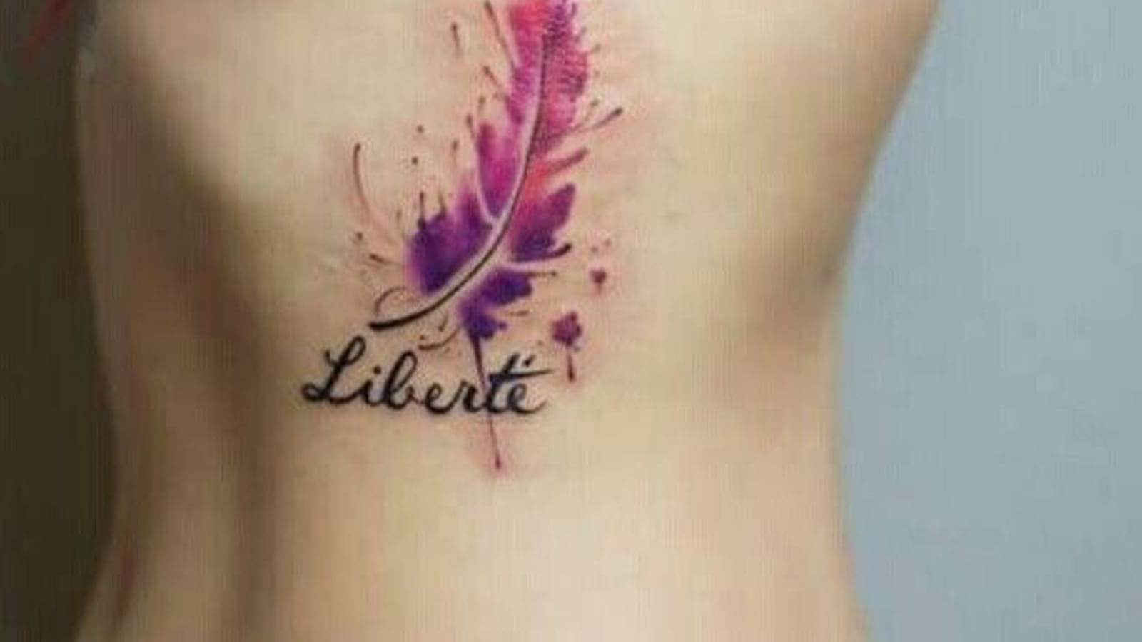 Tatouage plume et écriture sur le flanc