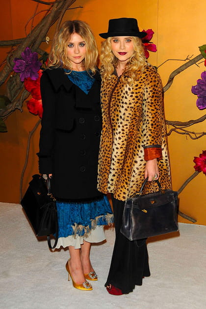 Mary-Kate Olsen en manteau léopard et chapeau, Ashley Olsen en robe à plumes bleue et manteau noir
