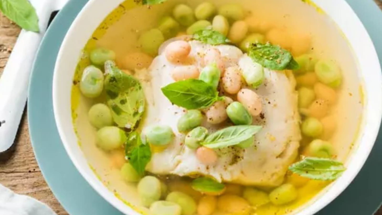 Filet de Merlu servi dans un bouillon de volaille au citron vert, haricots blancs, fèves et basilic frais