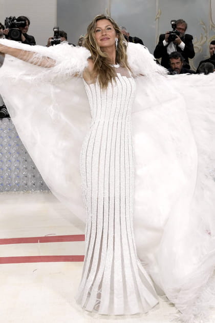 Gisele Bündchen en robe longue blanche et détails à plumes