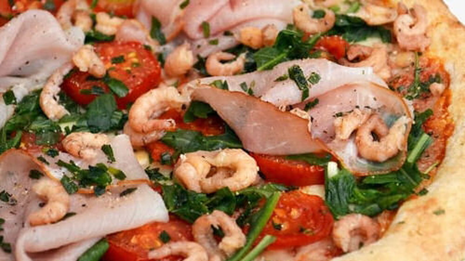 Pizza aux tomates cerise, jambon cru, crevettes grises, roquette et estragon