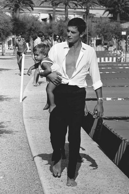 Alain Delon en chemise blanche ouverte et pantalon à pinces
