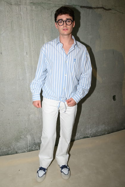 Noah Schnapp en chemise bleue rayée et pantalon blanc