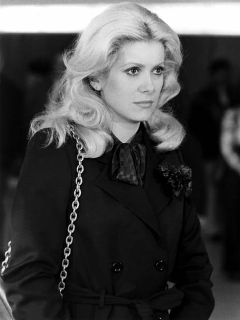 Catherine Deneuve en trench et chemise à col lavallière