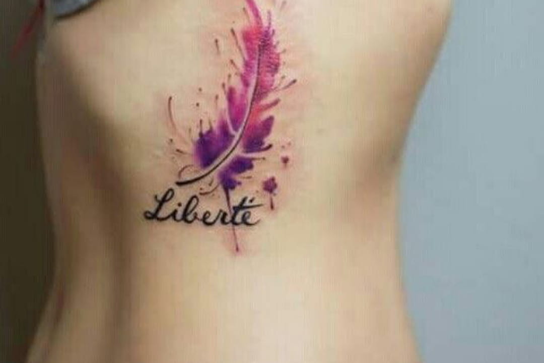 Tatouage plume et écriture sur le flanc