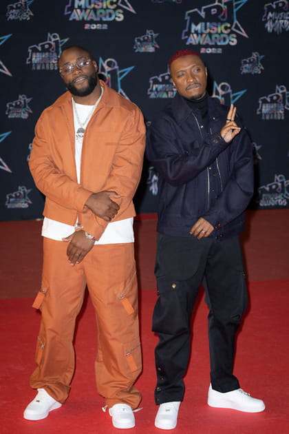 Soprano dans un look bleu avec pantalon baggy et Gradur dans un ensemble orange