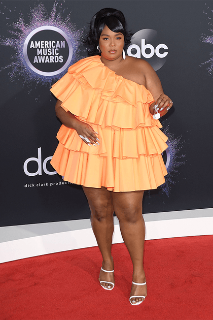 Lizzo en robe courte orange asym&eacute;trique &agrave; volants