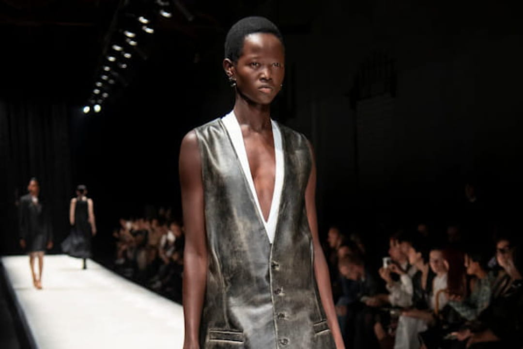 Veste en cuir sans manches, jupe noire et boots bleues aperçues sur le