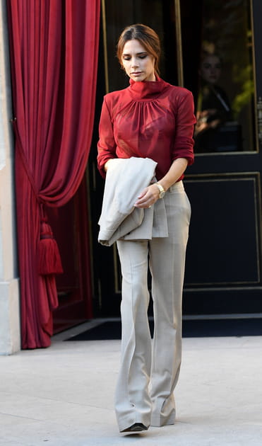 Victoria Beckham en pantalon gris clair et chemisier en voile rouge