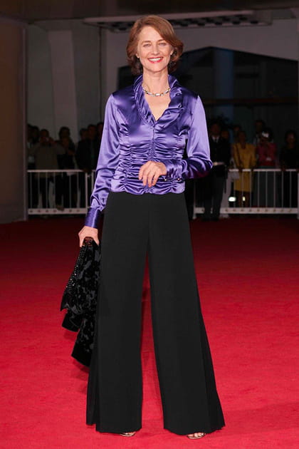 Charlotte Rampling en blouse irisée violette et pantalon noir