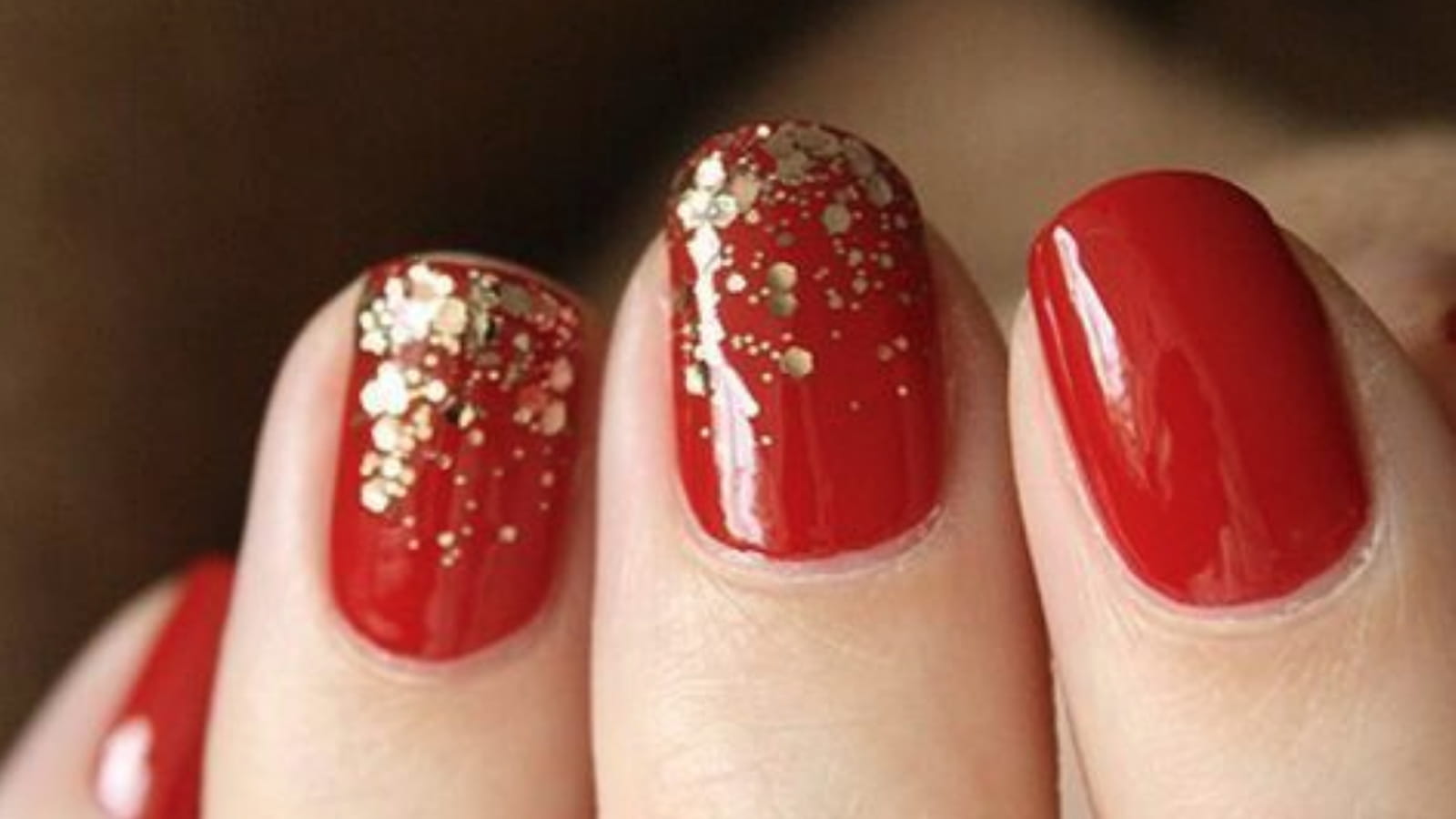 Des ongles rouges avec des paillettes dorées