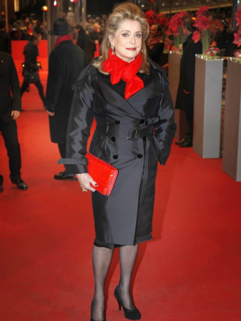 Catherine Deneuve en trench et écharpe rouge