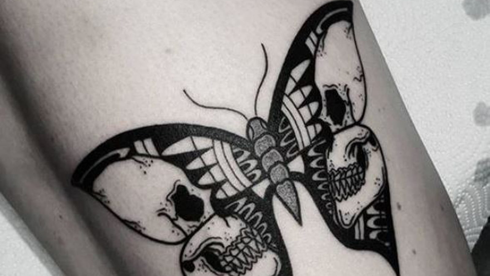 Têtes de mort et papillon sur la cuisse