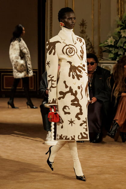 Manteau blanc &agrave; motifs caramel et sac &agrave; main rouge aper&ccedil;us sur le d&eacute;fil&eacute; Schiaparelli