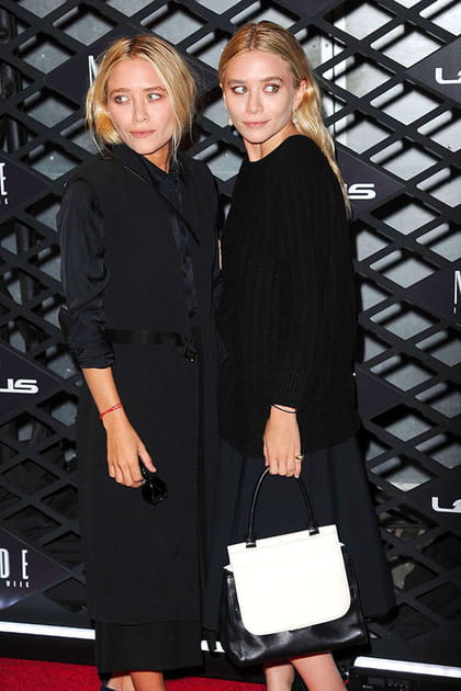 Mary-Kate Olsen en manteau sans manches noir, Ashley Olsen en jupe noire et pull fluide
