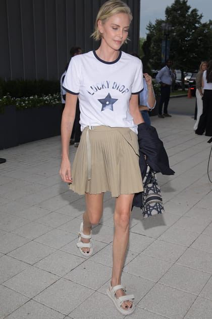 Charlize Theron en look Dior composé d'une mini-jupe beige et d'un t-shirt