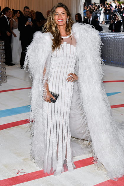 Gisele Bündchen en robe blanche semi-transparente et cape à plumes Chanel