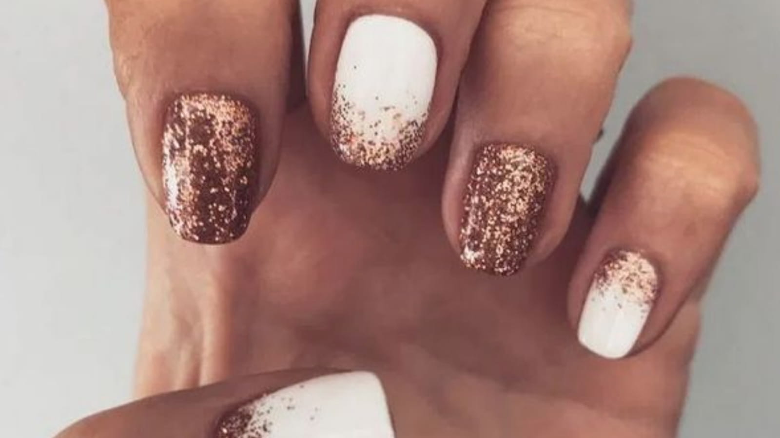 Des ongles blancs avec des paillettes rose gold