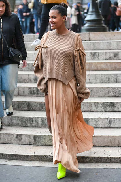 Tina Kunakey en pull beige à nœuds et jupe plissée Stella McCartney