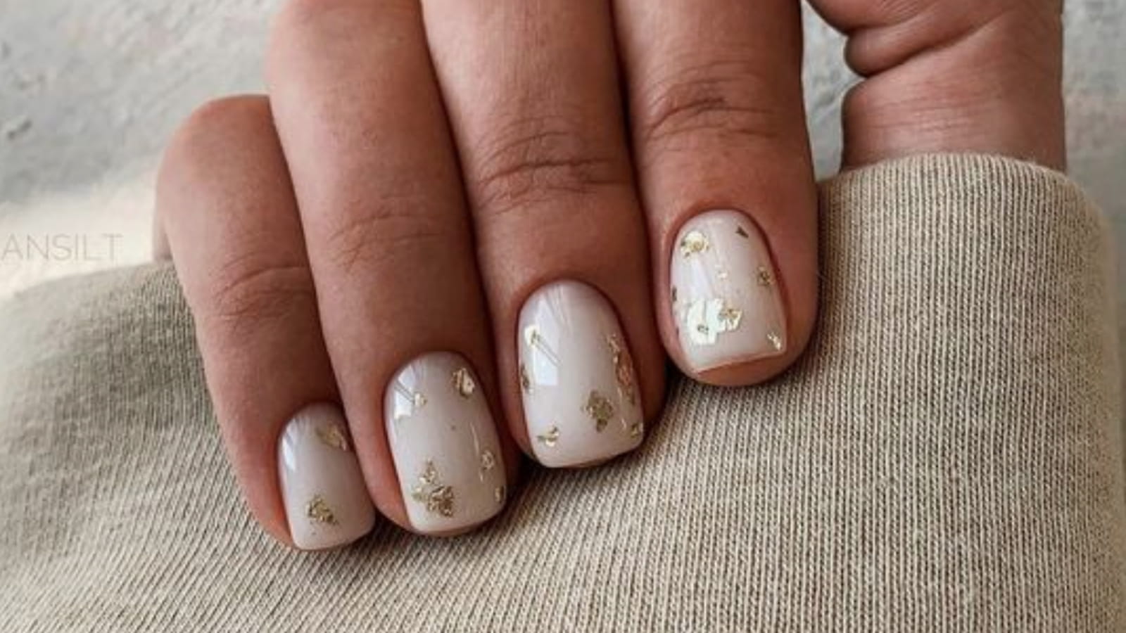 Des ongles blancs avec des paillettes dorées